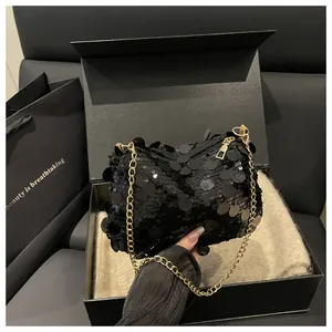 Detail of a black sequined mini bag with gold chain strap in a premium gift box set