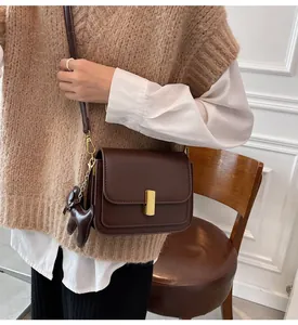 Vue détaillée d'un sac à bandoulière carré marron minimaliste avec boucle dorée.