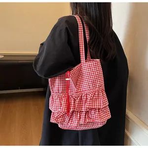 Détail du sac cabas à carreaux rouges avec des volants et un cordon latéral