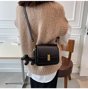 Vue détaillée d'un sac à bandoulière carré noir avec fermoir doré et accessoire