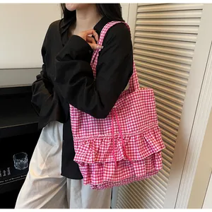 Gros plan du sac cabas à carreaux roses avec volants et cordon de serrage décoratif