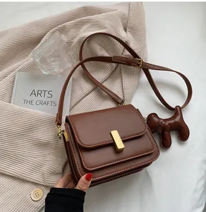 Vue détaillée d'un sac bandoulière marron en cuir avec un charme de chien