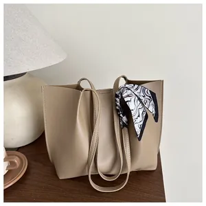 Detail of beige tote bag featuring elegant black and white wavy pattern silk scarf handle