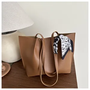 Close-up of brown faux leather tote bag with stylish black and white patterned silk scarf