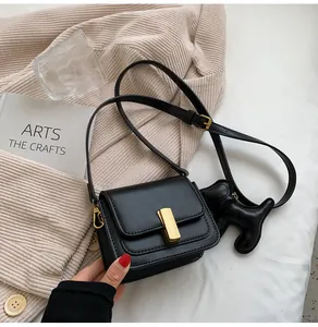Vue détaillée d'un sac bandoulière noir avec fermoir doré et charmant pendentif chiot noir