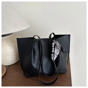 Close-up of black pleated leather tote bag featuring a decorative silk scarf on the handle