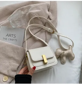 Gros plan d'un petit sac carré blanc avec un charmant pendentif en forme de chien