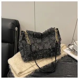 Detailed close-up of textured checkered handbag with gold chain on beige fabric