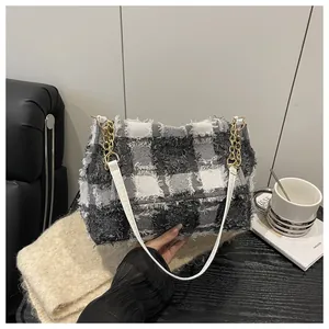 Close-up of black and white checkered tweed shoulder bag with gold chain strap