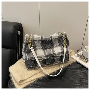 Detail of checkered tote bag with frayed edges and golden metal chain strap