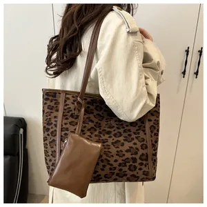 Detail view of large leopard print tote bag with brown leather handles and small pouch
