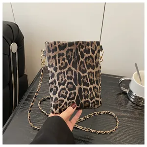 Detail of leopard print suede mini square bag featuring a gold chain strap