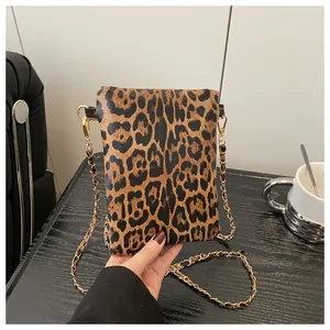 Detailed close-up of a leopard print crossbody bag featuring a golden chain strap