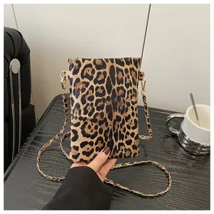 Detail of leopard print mini crossbody bag with gold chain strap on a dark table