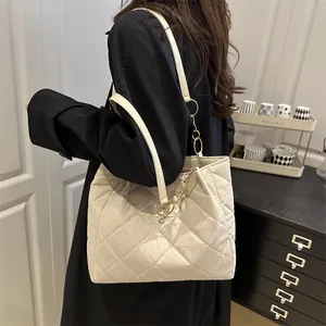 Borsa tote trapuntata beige con catena dorata mostrata sulla spalla della modella