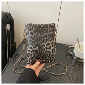 Close-up of leopard print crossbody bag with golden chain strap and leather details