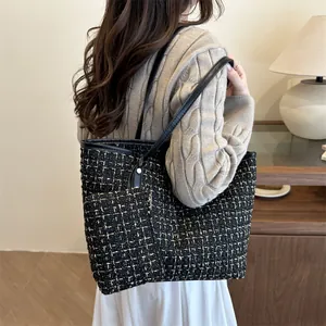 Elegant black and gold tweed tote bag with matching pouch shown on a model
