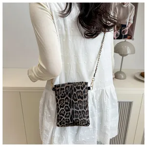 Detail of leopard print crossbody bag with gold chain strap on white lace dress