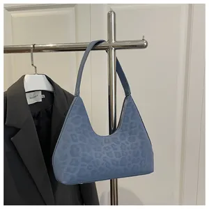 Detail der blauen Schultertasche mit Leopardenmuster, Logo-Prägung und Reißverschluss