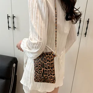 Stylish leopard print crossbody bag with gold chain strap shown on model profile