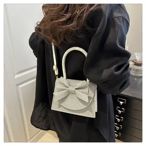 Silver glitter crossbody bag with a large bow detail shown on a model for size perspective