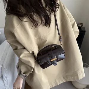 Elegant dark brown leather crossbody bag with gold hardware shown on a female model