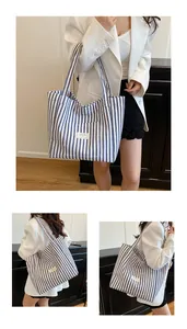 Detail of blue striped canvas tote bag with woven label and long shoulder straps