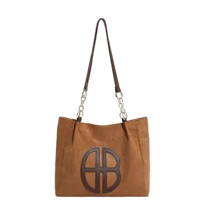 Brown faux suede tote bag with leather AB logo patch and gold chain strap detail