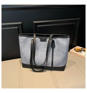 Détail du cabas en feutre gris et cuir noir avec logo tendance et doubles anses fines
