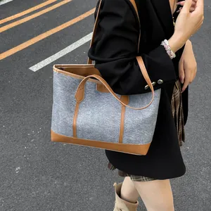 Grand sac cabas minimaliste en feutre gris et cuir marron porté par un mannequin