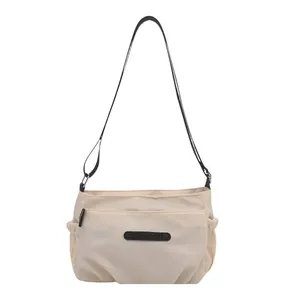 Minimalist cream nylon crossbody bag with adjustable black strap and multi-pocket design