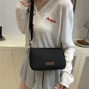 Chic black water-resistant nylon crossbody bag with adjustable strap and fashion patch