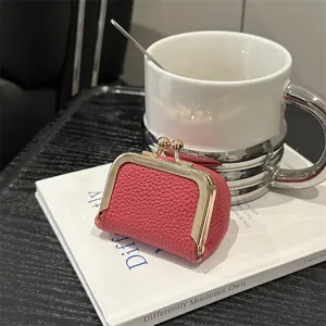 Mini pochette en cuir rouge pour bijoux et pièces sur un livre de décoration blanc