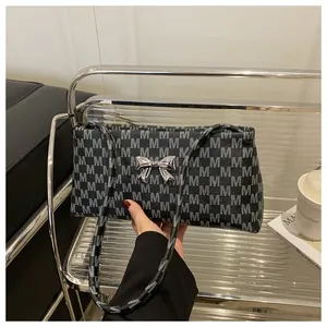 Dettaglio del fiocco in metallo argentato e motivo monogramma grigio sulla borsa a tracolla