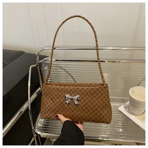 Dettaglio della texture in pelle marrone e della fibbia a fiocco argento sulla borsa a tracolla