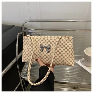 Dettaglio della borsa crema con motivi ad anelli vintage rossi e fibbia a fiocco argento