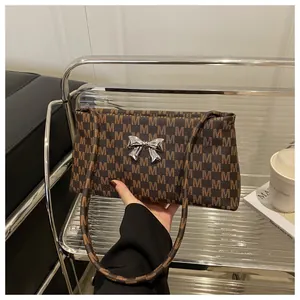 Dettaglio della borsa a tracolla marrone monogramma con fiocco in metallo argentato