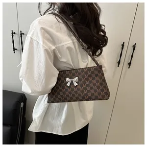 Vista dettagliata della borsa vintage marrone con motivo M e fiocco in argento