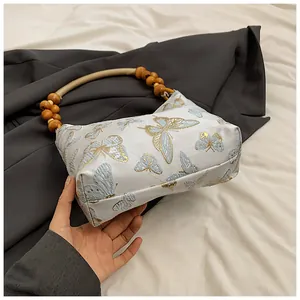 Detail des Holzperlengriffs und der Schmetterlingsstickerei auf der weißen Tasche