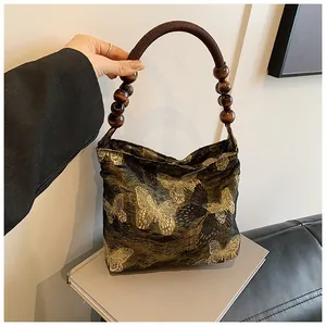Detail der Vintage-Webtasche mit Schmetterlingsstickerei und Holzperlen-Handgriff