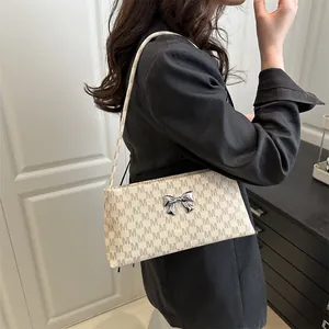 Borsa a spalla beige chic con stampa di lettere e fiocco argento indossata da modella