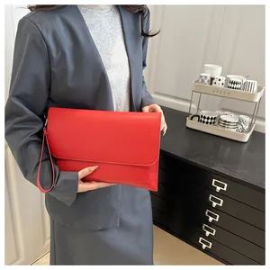 Detail of red PU leather envelope clutch bag held by model in professional grey suit