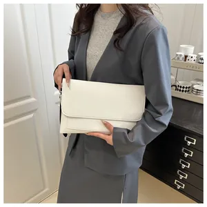 Close-up of a minimalist white PU leather envelope clutch bag held by a model in lifestyle setting