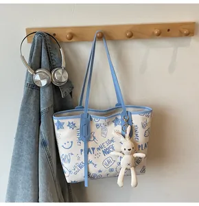 Close-up of contrast tote bag with graffiti prints, rabbit plush charm and blue trim