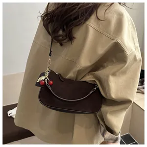 Detail of dark brown suede crescent bag featuring a stylish cherry pendant charm