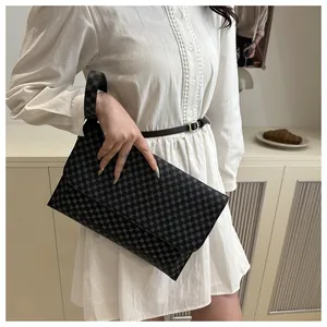 Close-up of black envelope clutch featuring silver geometric dots and wristlet strap