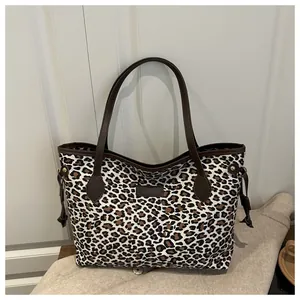 Détail du sac cabas léopard avec anses en cuir marron et fermeture à cordon coulissant