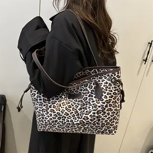 Grand sac cabas imprimé léopard avec anses en cuir marron porté par un mannequin en manteau