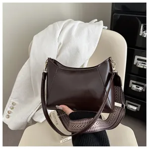 Close-up of chocolate brown glossy leather handbag with wide herringbone woven strap