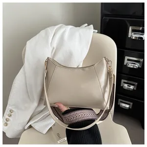 Detail of beige PU leather shoulder bag featuring a wide jacquard woven strap and gold hardware